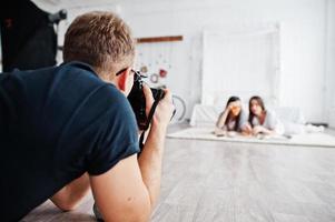 hombre fotógrafo disparando a las gemelas de estudio que están comiendo pizza. fotógrafo profesional en el trabajo. foto