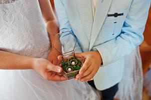 niños manos sosteniendo anillos de boda en caja en la ceremonia de la iglesia. foto