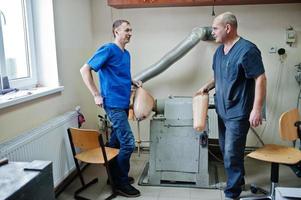 dos trabajadores protésicos que fabrican una pierna protésica mientras trabajan en el laboratorio. foto