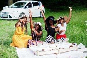 grupo de chicas afroamericanas celebrando la fiesta de cumpleaños y tintineando vasos al aire libre con decoración. foto