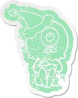 cartoon distressed sticker of a cyclops alien spaceman wearing santa hat vector