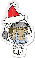 distressed sticker cartoon of a crying astronaut wearing santa hat vector