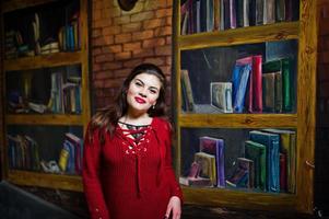 Brunette plus size model against wall like library. photo