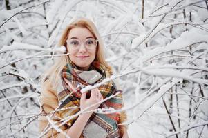 Portraiy of blonde girl in glasses, red fur coat and scarf at winter day. photo