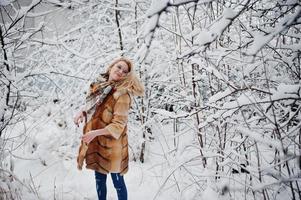 retrato de chica rubia con gafas, abrigo de piel rojo y bufanda en el día de invierno. foto