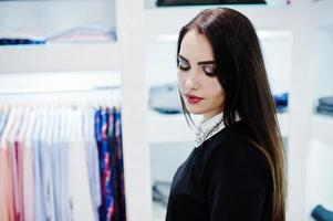 Brunette gorgeous girl in the clothing store boutique at black dress. photo