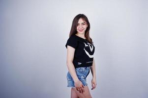 Portrait of an attractive girl in black t-shirt saying lol and denim shorts posing in the studio. photo