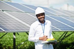 técnico afroamericano revisa el mantenimiento de los paneles solares. ingeniero de hombre negro en la estación solar. foto