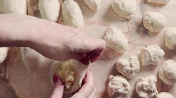 las manos de las mujeres hacen pasteles de masa en la cocina casera. video
