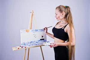 Beautiful woman artist painter with brushes and oil canvas posing in studio isolated on white. photo