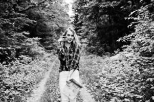 retrato de una hermosa joven con camisa de tartán tomando fotos con cámara en el bosque.