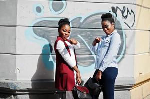 dos elegantes amigas afroamericanas con bolsos posaron al aire libre de la ciudad de steets. foto