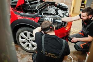 el trabajador del servicio de automóviles puso una película antigrava en una carrocería roja en el taller de detalles del vehículo. protección del automóvil con películas especiales. foto