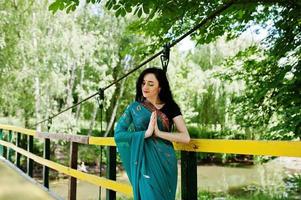 Portrait of beautiful indian brumette girl or hindu woman model on bridge. Traditional Indian costume lehenga choli. photo