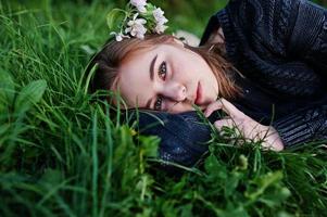 Young brunette girl lying on green grass with branches of blossom tree. photo