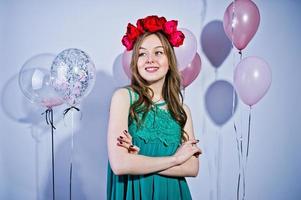 Happy girl in green turqoise dress and wreath with colored balloons isolated on white. Celebrating birthday theme. photo