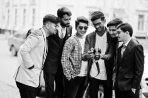 Group of six south asian indian mans in traditional, casual and business wear. Asia tourists looking at the dslr photo camera.