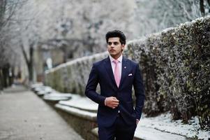 Elegant indian macho man model on suit and pink tie posed on winter day. photo