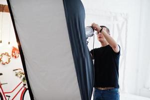 Photographer adjusts the flash light on studio. photo