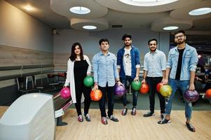 Group of five south asian peoples having rest and fun at bowling club. Holding bowling balls at hands. photo