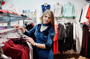 Blonde girl in blue dress in the clothing store boutique. photo