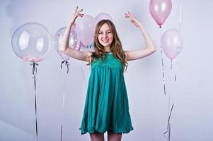 chica feliz con vestido verde turquesa con globos de colores aislados en blanco. celebrando el tema del cumpleaños. foto