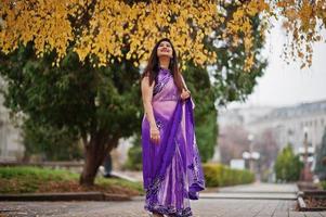 niña hindú india en el sari violeta tradicional posó en la calle otoño. foto