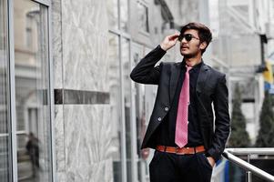 joven indio con traje, corbata y gafas de sol posó al aire libre. foto