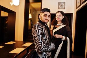 Lovely indian couple in love, wear at saree and elegant suit, posed on restaurant. photo