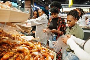 Group of african womans with shopping carts near baked products at a supermarket. photo