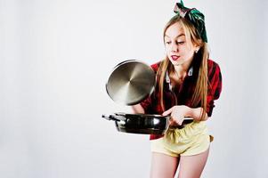 Young funny housewife in checkered shirt and yellow shorts pin up style with frying pan isolated on white background. photo