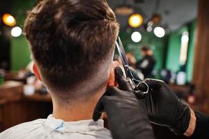 Handsome bearded man at the barbershop, barber at work. photo