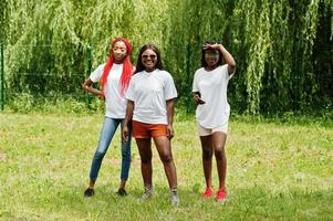 Three african american womans in park at white t-shirts. photo