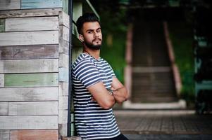 apuesto modelo de hombre de barba árabe alto en camisa despojada planteada al aire libre. chico árabe de moda. foto