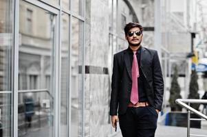 Young indian man on suit, tie and sunglasses posed outdoor. photo