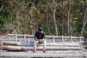 South asian agronomist farmer sitting on woods at farm. Agriculture production concept. photo