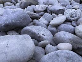 guijarros grises suaves en la playa, patrón y textura de piedras, meditación zen, fondo natural. foto