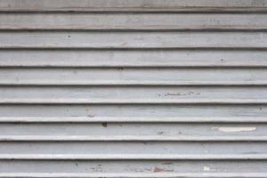 Grey aluminum automatic garage shutter closeup, steel striped sliding door, texture and pattern, old and weathered surface, dirty grunge background. photo