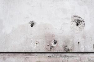 grey dirty concrete wall with holes, pattern and texture, weathered textured surface, grunge background photo