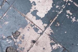 Blue peeling paint on the broken cement pavement, pattern and texture, colorful background, weathered textured surface photo