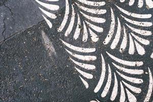 White leaf print on the weathered black asphalt, pattern and texture, weathered textured surface. photo