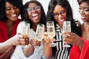 grupo de chicas africanas de fiesta tintineando copas con champán de vino espumoso. foto