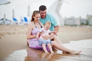 Summer vacations. Parents and people outdoor activity with children. Happy family holidays. Father, pregnant mother, baby daughter on sea sand beach. photo