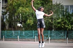 African american dark skinned slim model posed in a black leather shorts and white t-shirt. photo