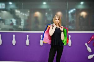 chica con bolsas de compras en el centro comercial contra la pared del club de bolos. foto