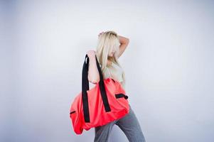 Chica rubia deportiva con una gran bolsa deportiva posada en el estudio con fondo blanco. foto