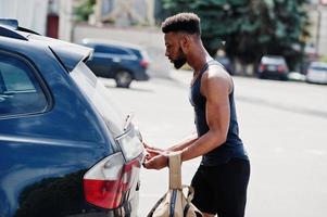 African american male athlete sport man with backpack against his black suv car before training. photo