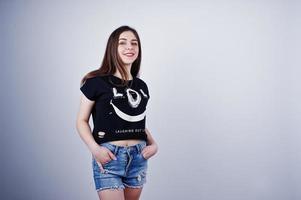 retrato de una chica atractiva en camiseta negra diciendo jajaja y pantalones cortos de mezclilla posando en el estudio. foto