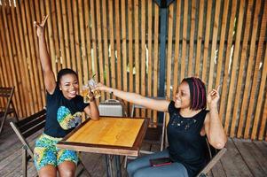 Two african american girls drinking and cheering together. photo