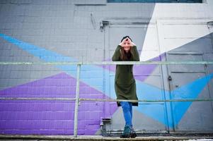 Young girl posed against colored wall in cold day. photo